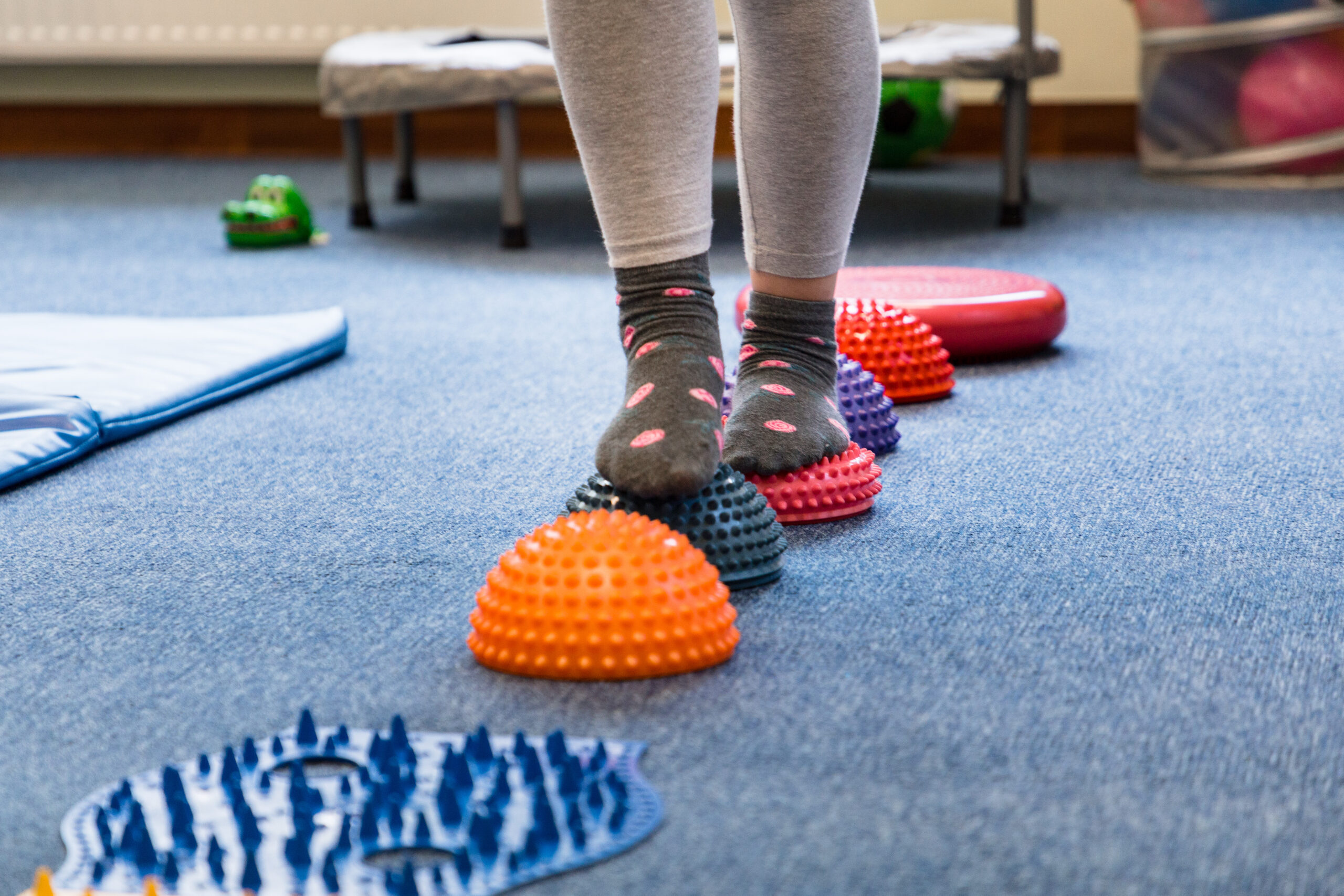 Child practicing balance and coordination by walking across sensory pods in a physiotherapy session